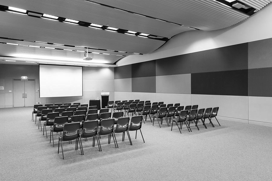 A room in the conference centre set up for a training seminar with a large projector screen and rows of chairs.