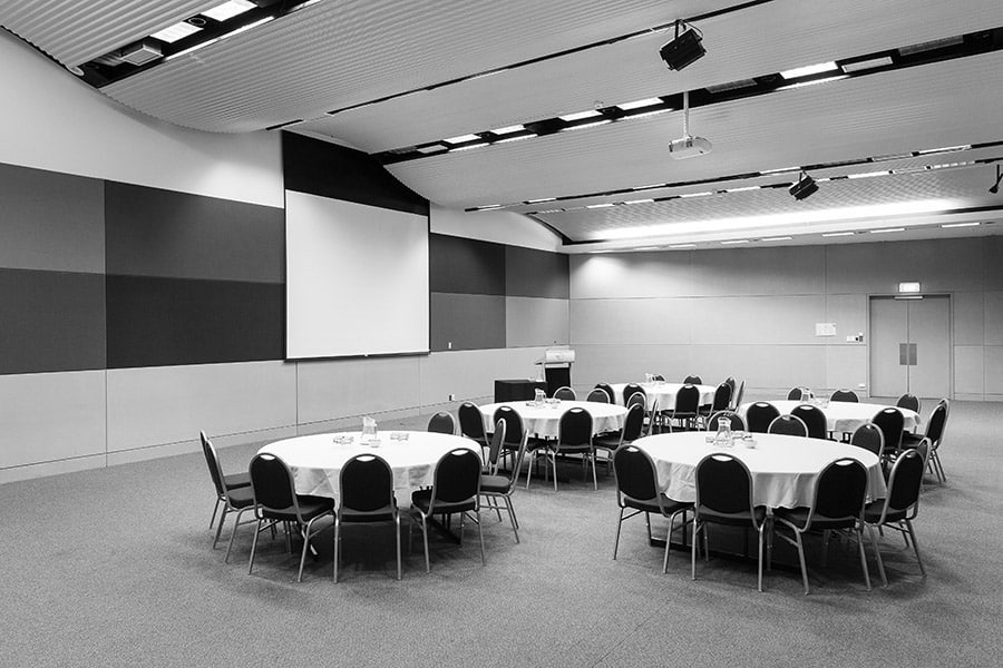 A large room in the conference centre set up for an event with circle tables and chairs.