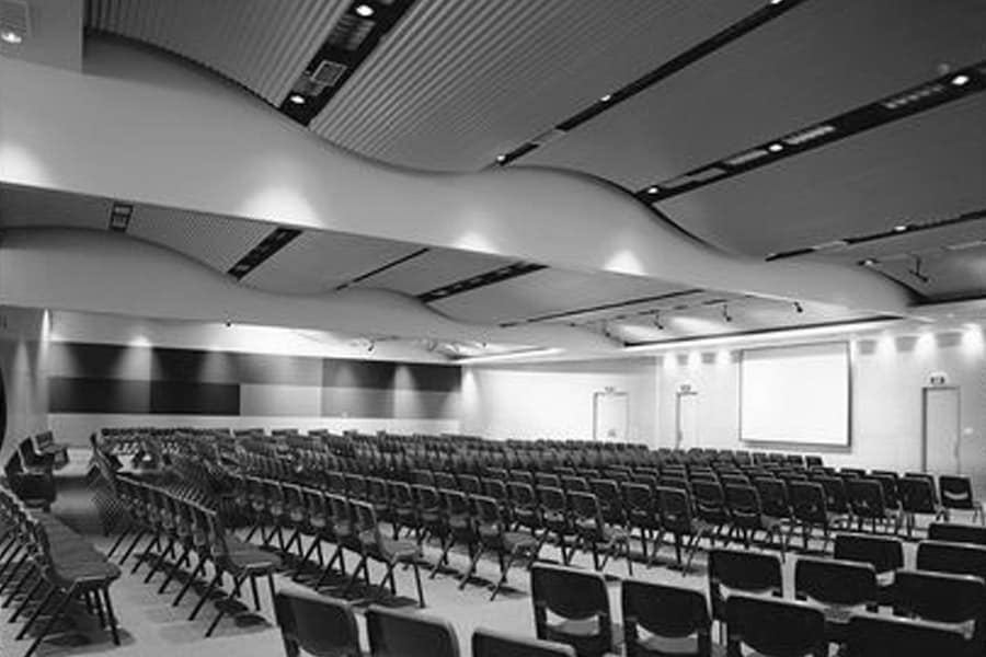 A large auditorium in the conference centre is set up for a large event with rows of seating and a large projector.