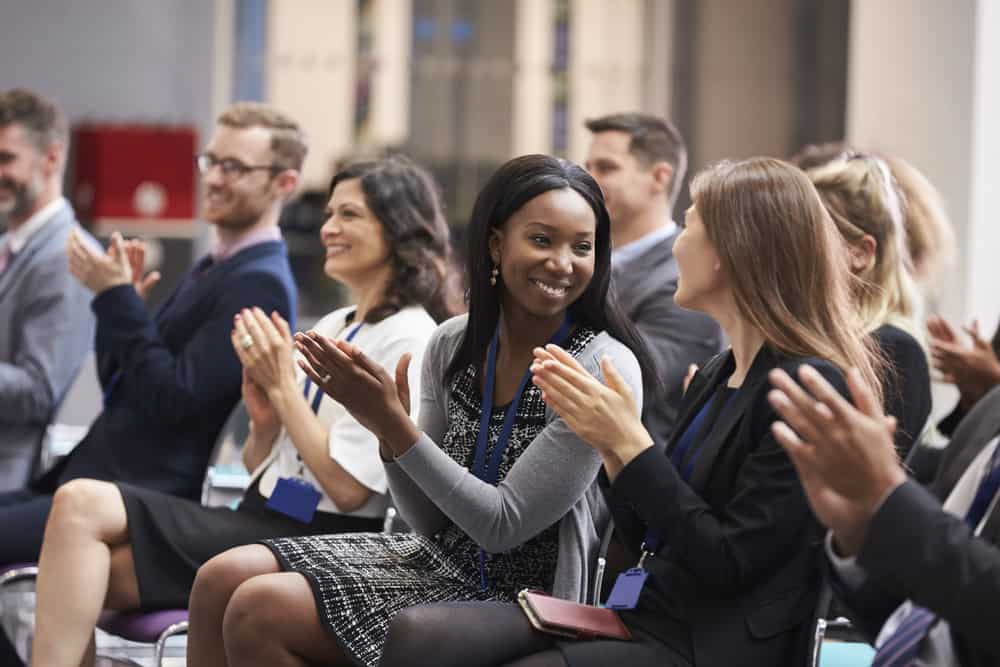 Adults applauding a speaker after a conference presentation.