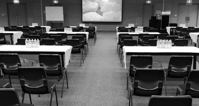 Tables and chairs are arranged in rows facing a large projector screen ready for a training seminar in the Everest room.